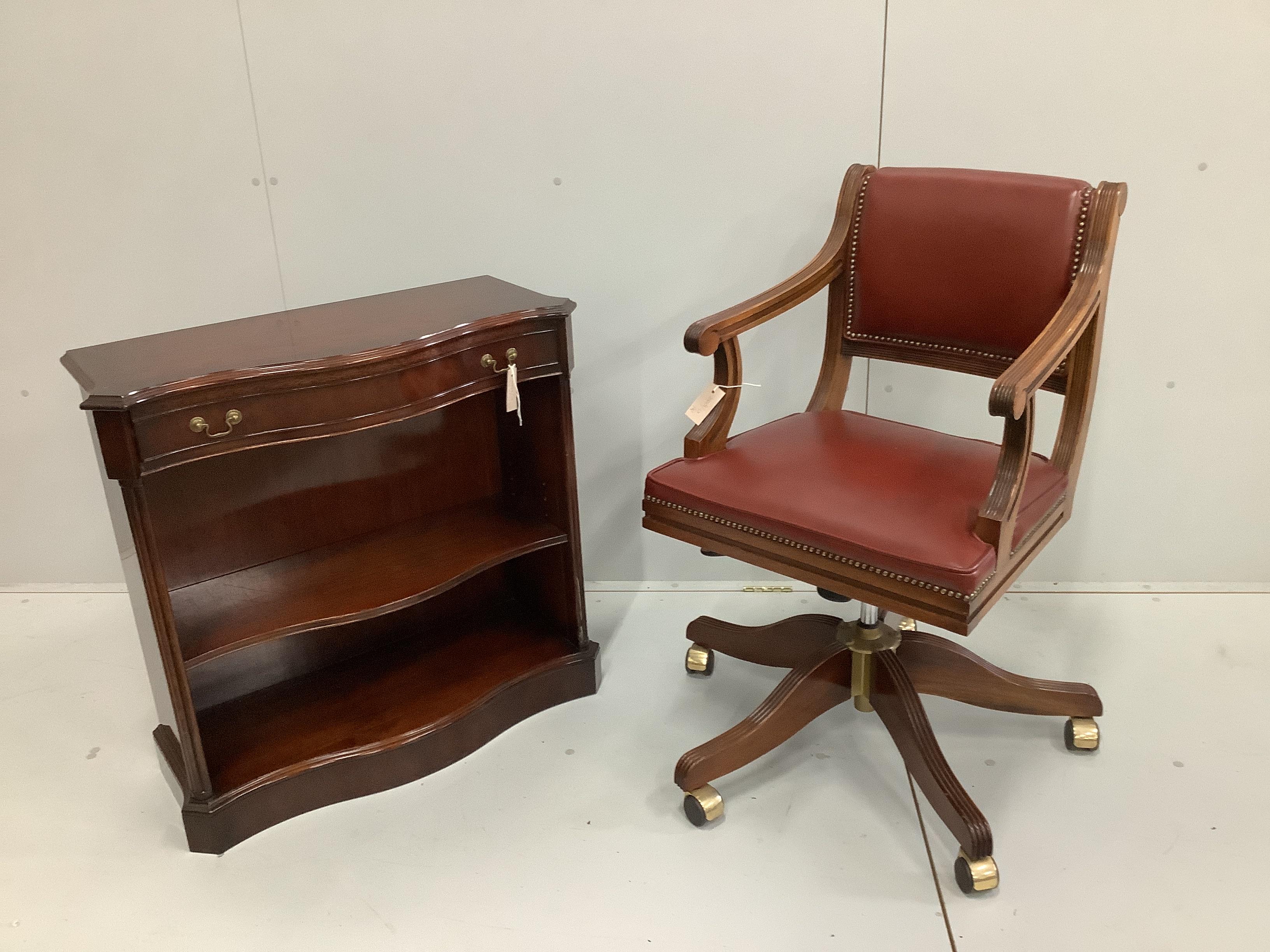 A reproduction mahogany framed swivel desk armchair, upholstered in red leather, width 54cm, height 95cm together with a small reproduction mahogany serpentine open bookcase, width 79cm, height 77cm